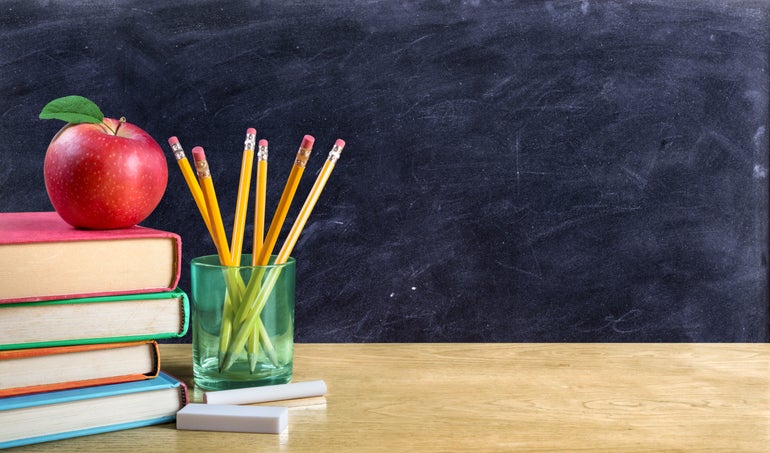 Desk with books apple and a blackboard